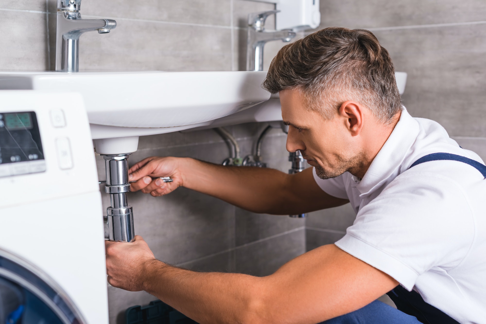 adult plumber fixing sink at bathroom